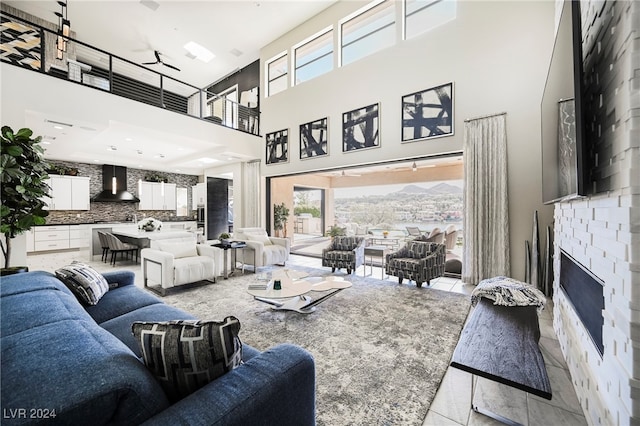 living room featuring a towering ceiling, a fireplace, a tray ceiling, and light tile patterned floors