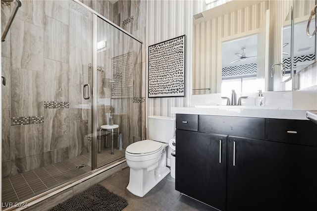 bathroom with vanity, toilet, ceiling fan, and a shower with shower door