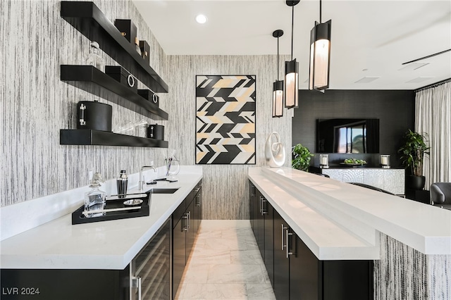 bar featuring beverage cooler, sink, and hanging light fixtures