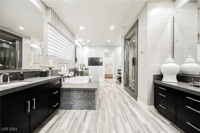 bathroom featuring plus walk in shower, tile walls, and vanity