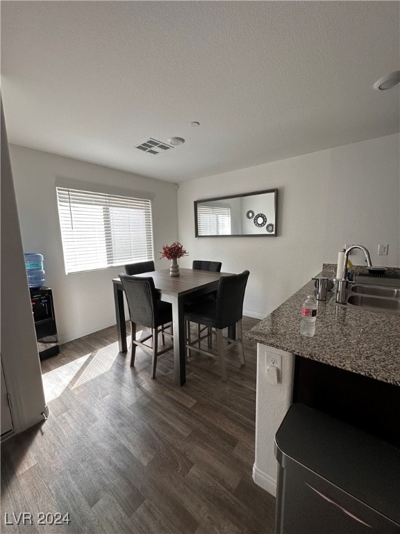 dining space with a textured ceiling, sink, and dark hardwood / wood-style flooring