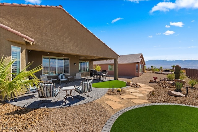 rear view of property with an outdoor living space, a mountain view, and a patio area