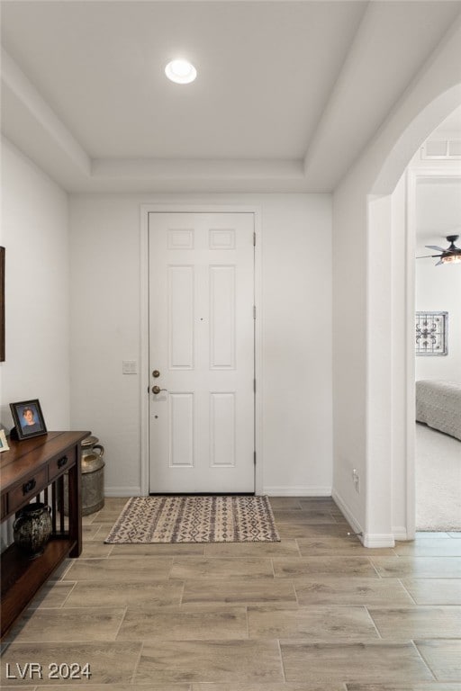 foyer featuring ceiling fan and a raised ceiling