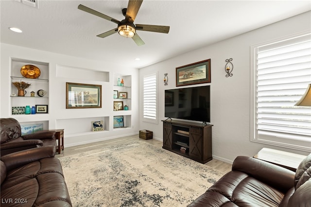 living room featuring light hardwood / wood-style flooring, built in features, and ceiling fan