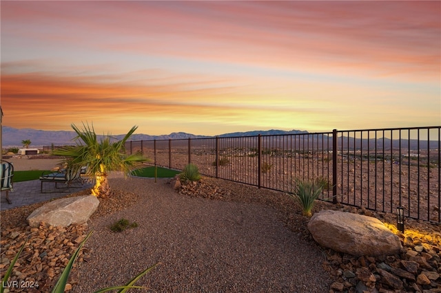 yard at dusk featuring a mountain view and a patio