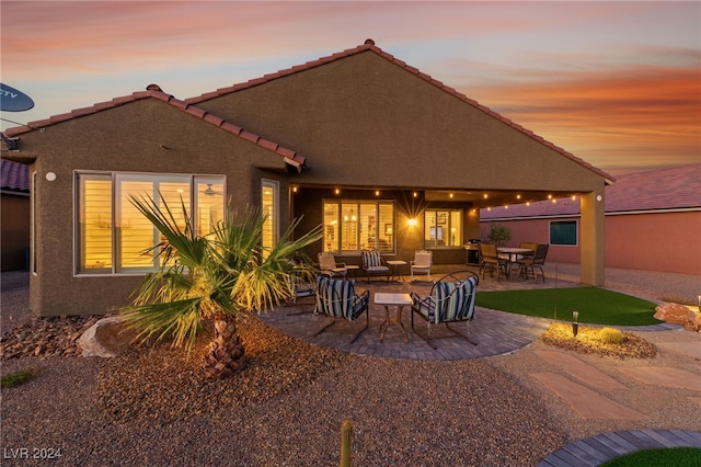 back house at dusk with an outdoor living space and a patio