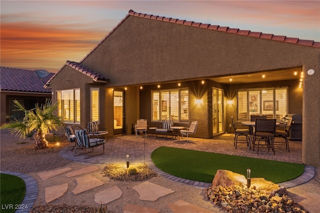 back house at dusk with a patio area