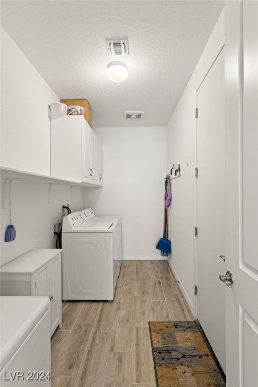 clothes washing area with cabinets and independent washer and dryer