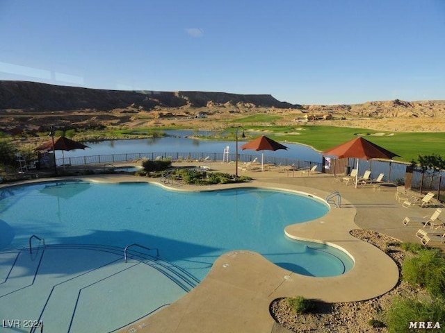 view of pool featuring a water and mountain view and a patio