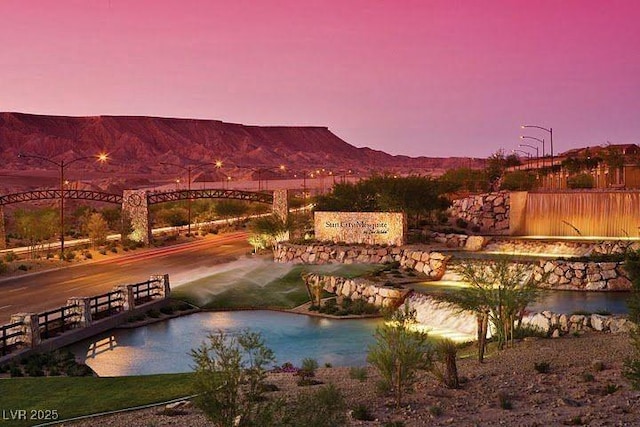 pool at dusk featuring a water and mountain view