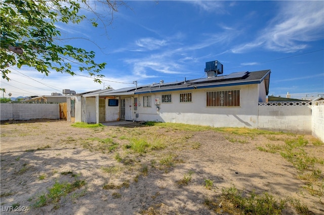 rear view of house with central air condition unit and solar panels