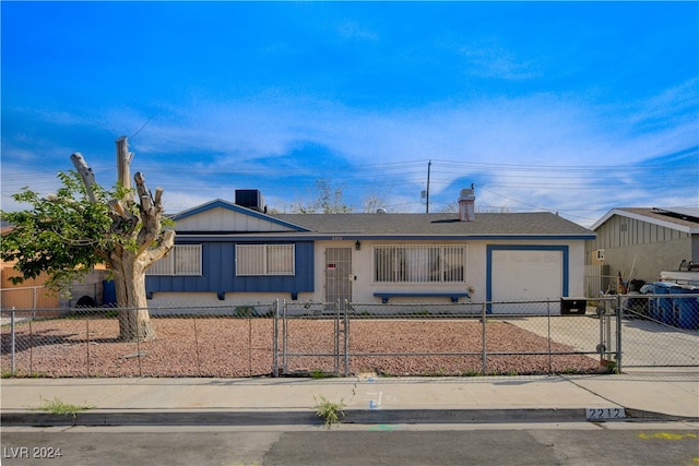 view of front of home with a fenced front yard, a garage, driveway, and a shingled roof