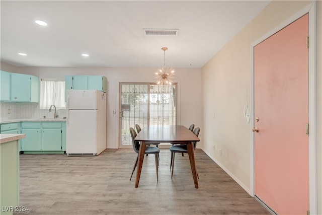 dining space featuring sink, a chandelier, and light wood-type flooring