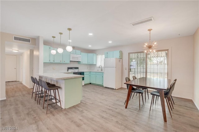 kitchen with a peninsula, white appliances, visible vents, and blue cabinets