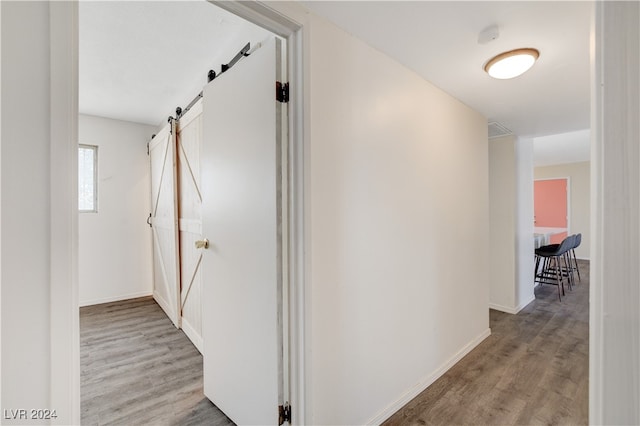 hallway featuring light wood-type flooring and a barn door