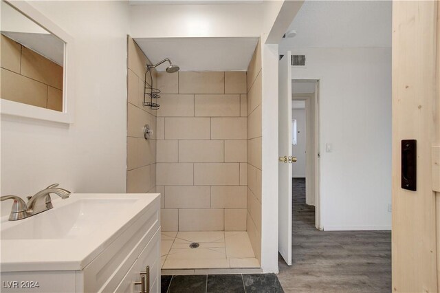 bathroom with tiled shower, vanity, and hardwood / wood-style flooring