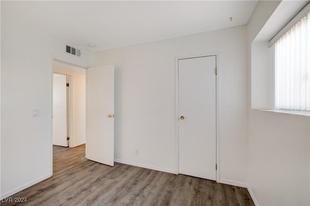 unfurnished bedroom featuring visible vents, baseboards, and wood finished floors