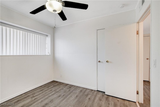 unfurnished bedroom with a ceiling fan, visible vents, wood finished floors, and baseboards