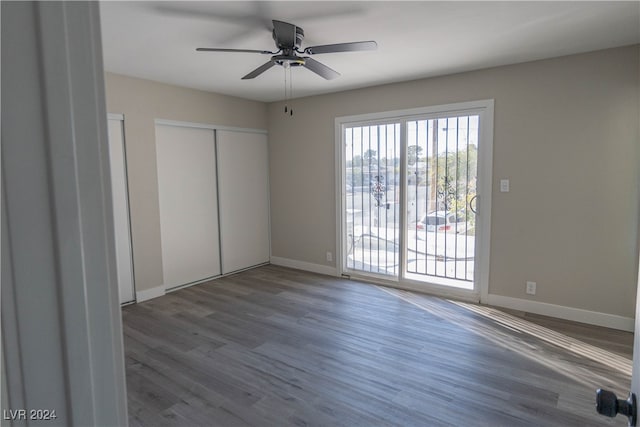 unfurnished bedroom with a closet, ceiling fan, dark hardwood / wood-style floors, and access to exterior