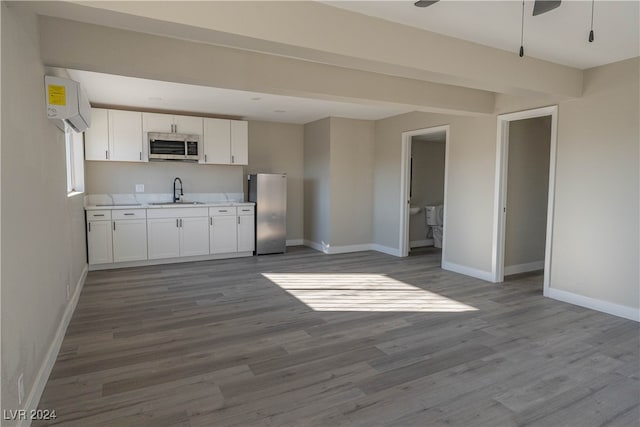 kitchen with hardwood / wood-style floors, appliances with stainless steel finishes, sink, white cabinetry, and ceiling fan