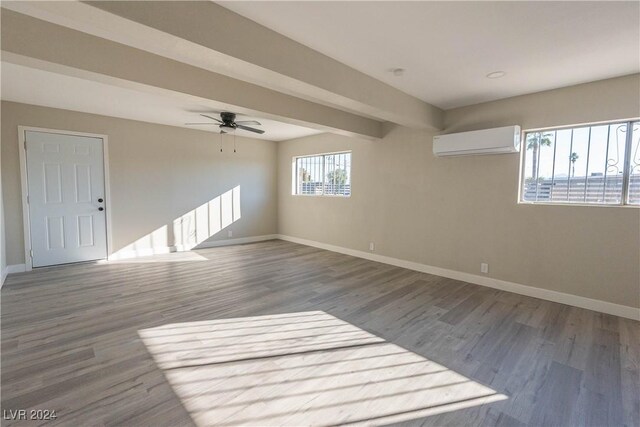 unfurnished room with ceiling fan, beamed ceiling, hardwood / wood-style flooring, and a wall mounted air conditioner