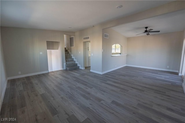 unfurnished living room with stairway, baseboards, visible vents, and dark wood-style flooring