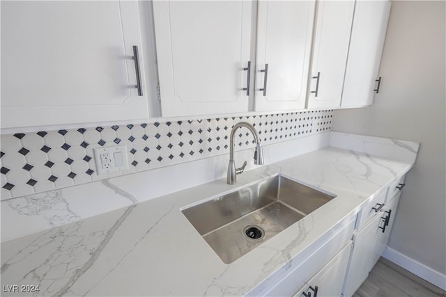 details featuring light stone counters, white cabinetry, and sink