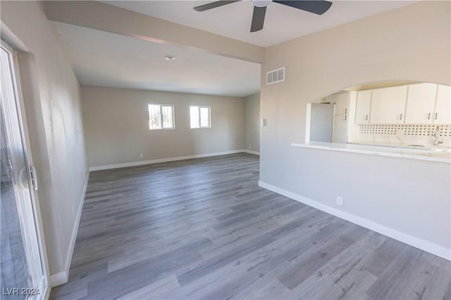 empty room featuring baseboards, visible vents, ceiling fan, and wood finished floors