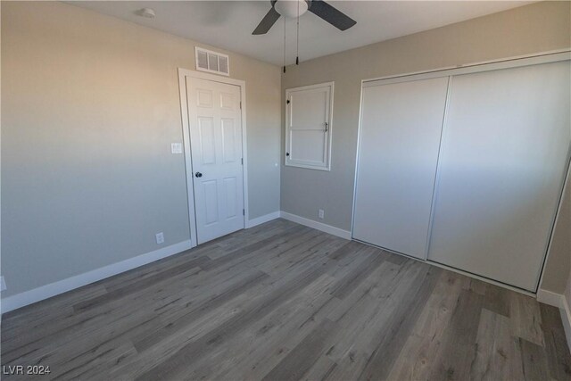 unfurnished bedroom with ceiling fan, a closet, and hardwood / wood-style flooring