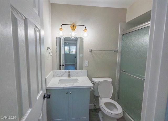 bathroom with vanity, toilet, and a shower with door