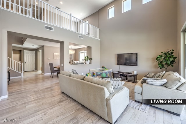 living room with a towering ceiling and light hardwood / wood-style flooring