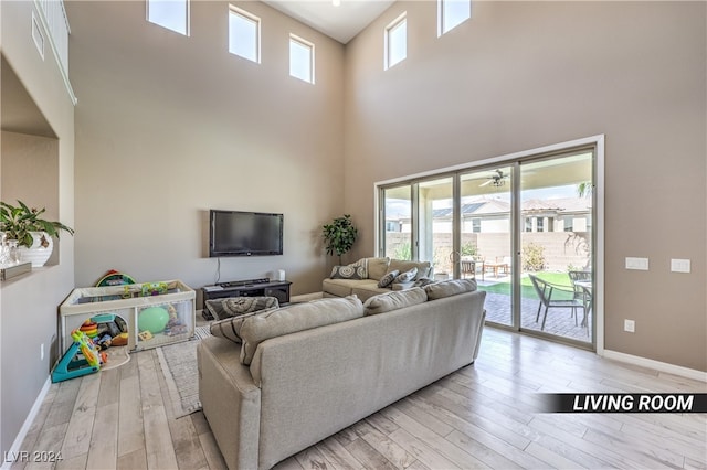 living room with a high ceiling, a wealth of natural light, and light hardwood / wood-style flooring