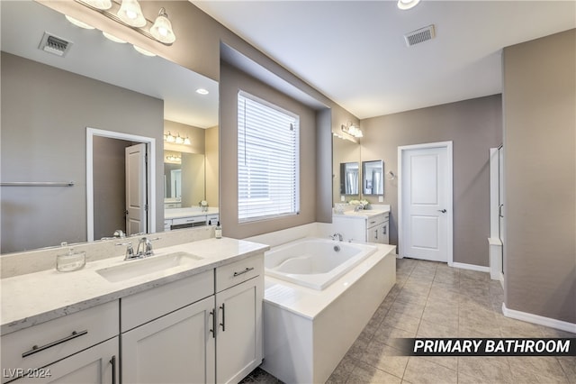 bathroom with tile patterned flooring, tiled tub, and vanity