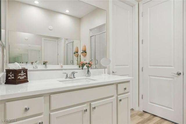 bathroom with hardwood / wood-style flooring, vanity, and a shower with shower door