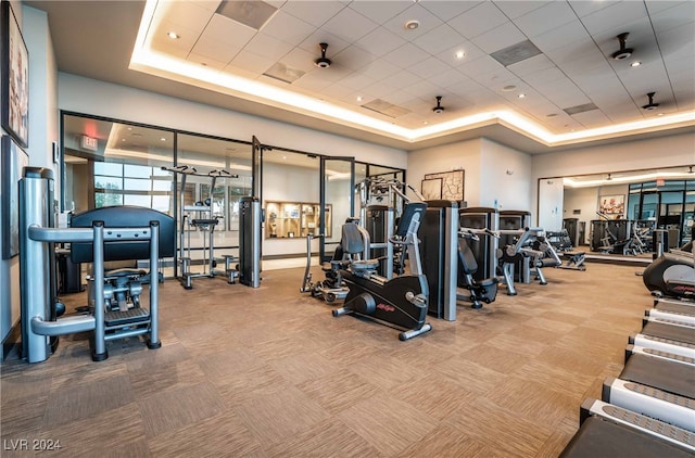 gym with carpet floors and a tray ceiling