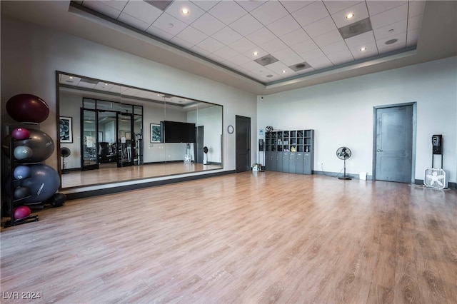 exercise room with a towering ceiling, hardwood / wood-style floors, and a tray ceiling