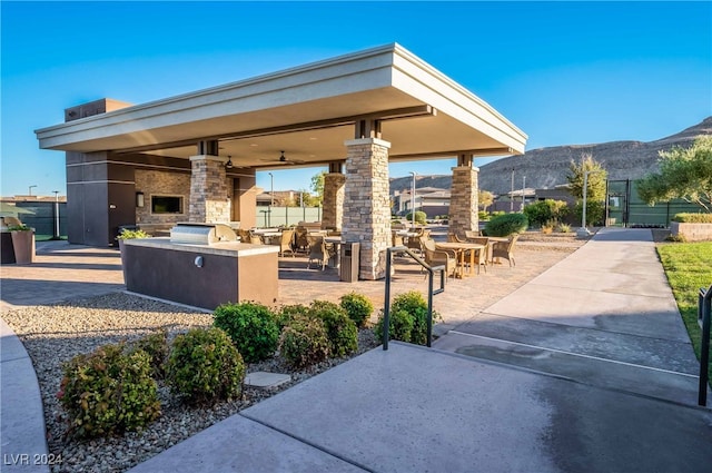 view of property's community with area for grilling, a mountain view, a patio, and a bar