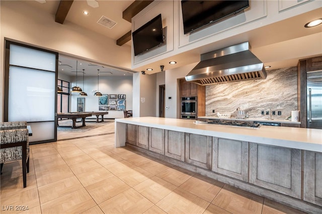 kitchen with beam ceiling, stainless steel appliances, tasteful backsplash, island range hood, and decorative light fixtures