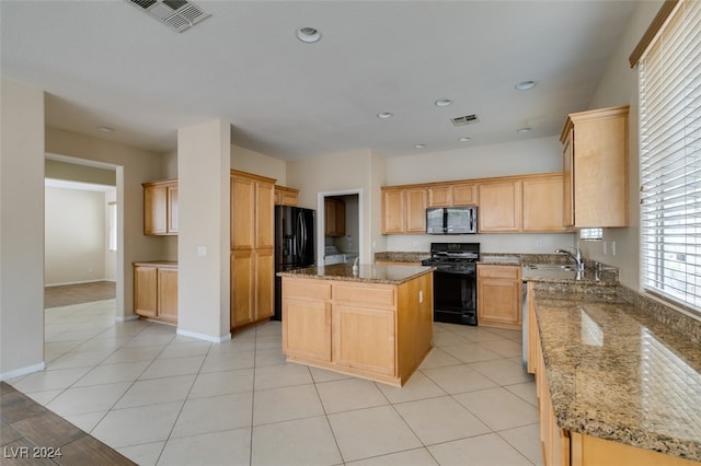 kitchen with black appliances, light brown cabinets, a kitchen island, and sink