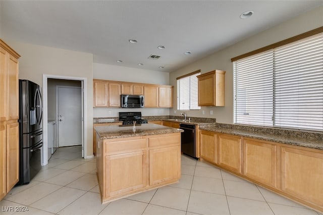 kitchen with black appliances, light tile patterned floors, a center island, and light brown cabinets