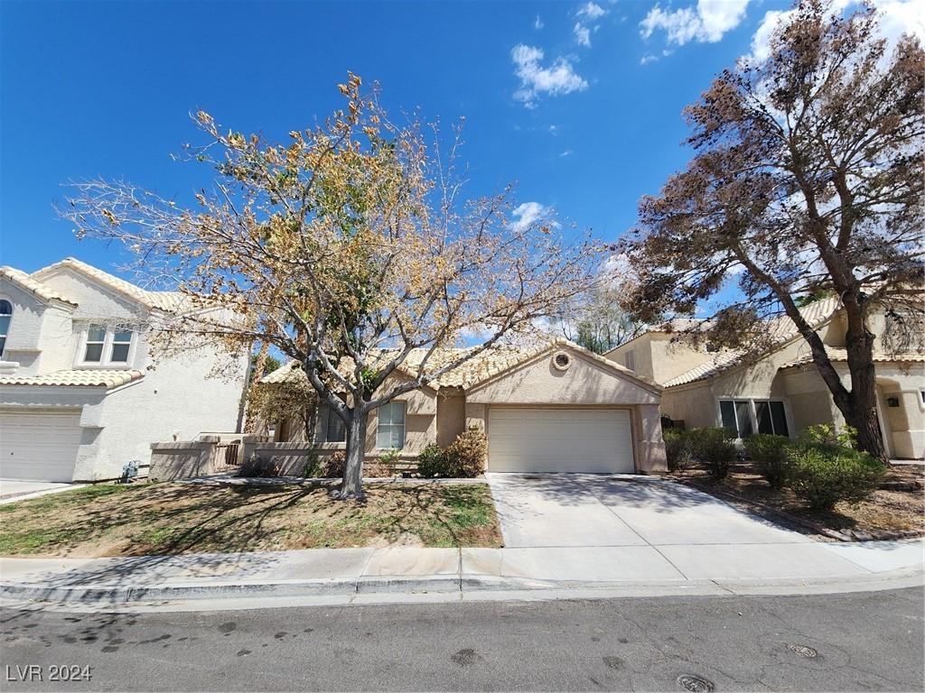 view of front of property featuring concrete driveway, an attached garage, a tile roof, and stucco siding