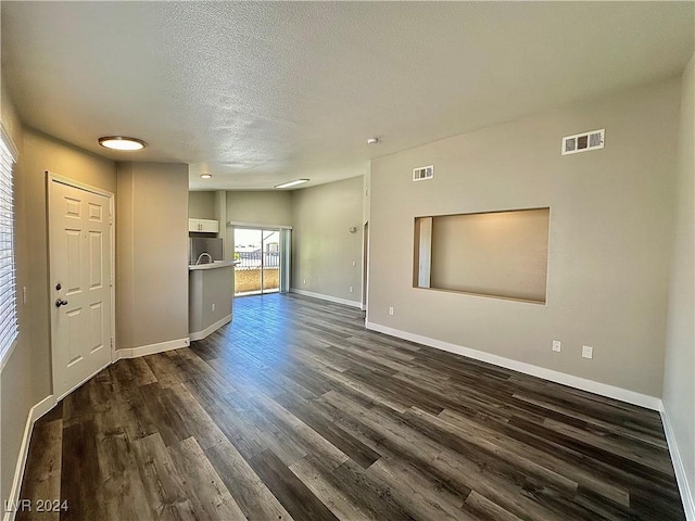 unfurnished living room with dark wood-type flooring and a textured ceiling