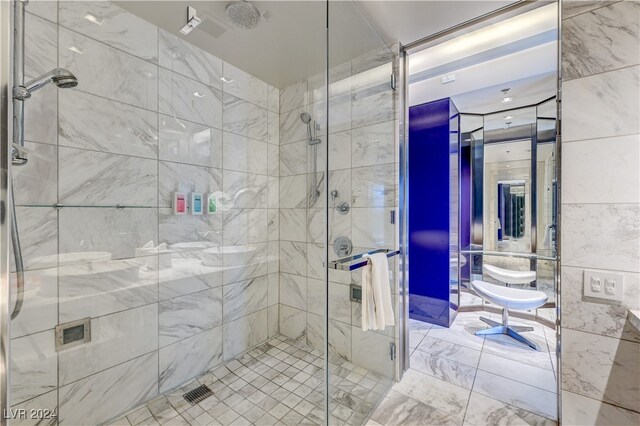 full bath featuring a stall shower, marble finish floor, and tile walls