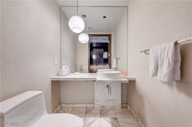 bathroom featuring toilet, marble finish floor, visible vents, and a sink