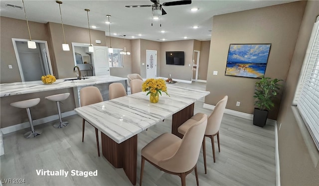 dining space with light hardwood / wood-style floors, ceiling fan, and sink