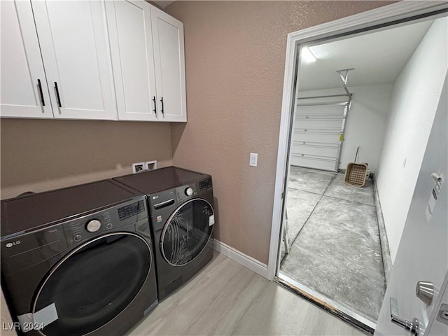 clothes washing area featuring cabinets, light wood-type flooring, and washer and clothes dryer