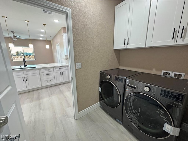 laundry area featuring cabinets, ceiling fan, sink, separate washer and dryer, and light hardwood / wood-style floors