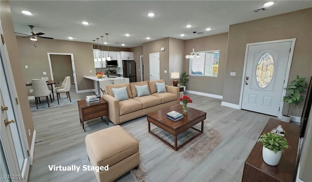 living room featuring ceiling fan with notable chandelier, light hardwood / wood-style flooring, and sink