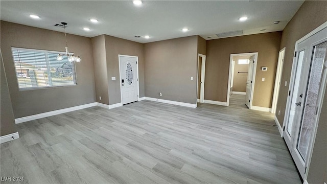 foyer with light hardwood / wood-style flooring and an inviting chandelier