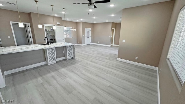 kitchen featuring pendant lighting, light hardwood / wood-style floors, light stone counters, and ceiling fan